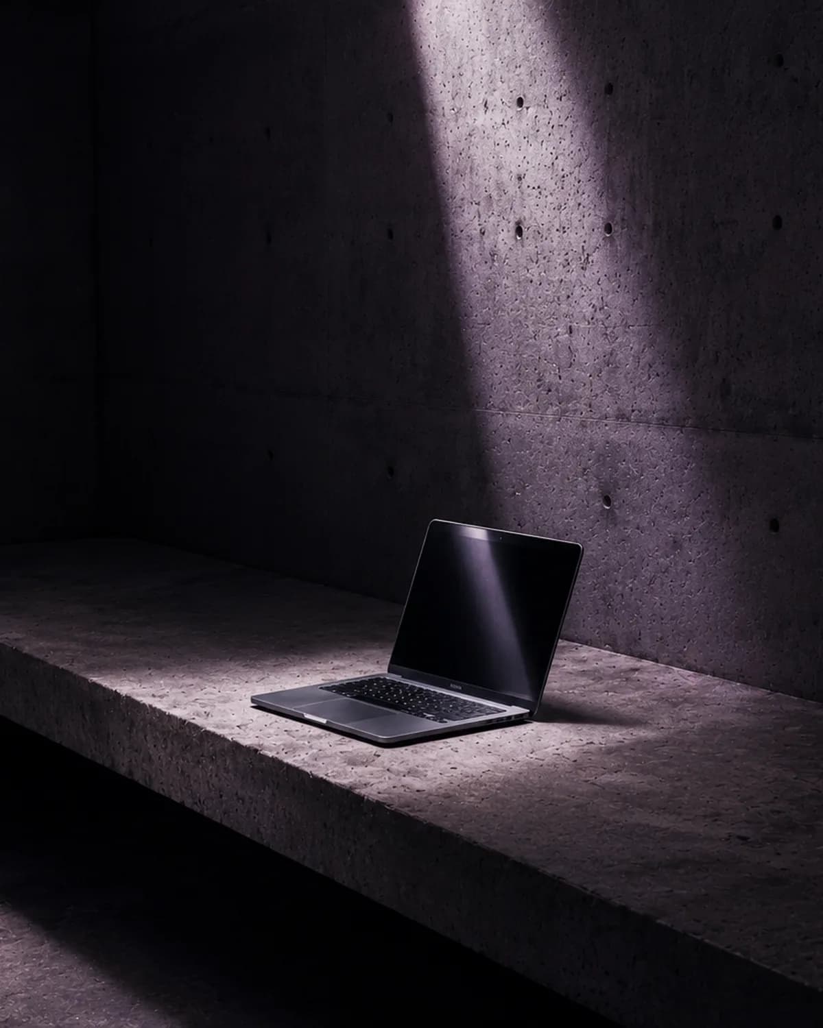 A laptop in a dimly lit concrete room, illustrative image for the article